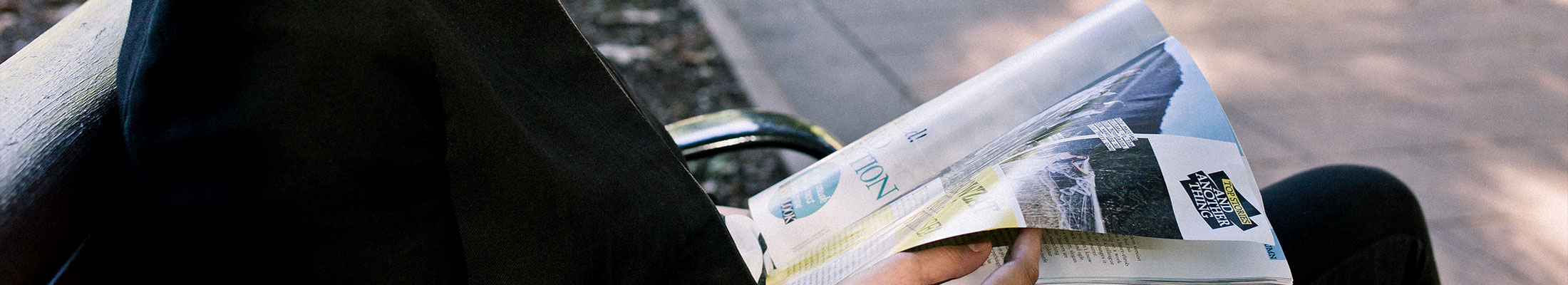 Person reading magazine on bench